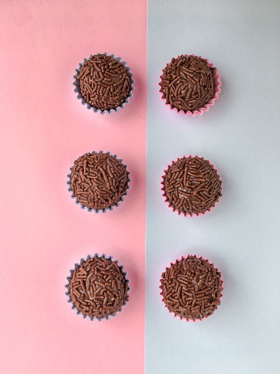 Seis brigadeiros dispostos em fileiras sobre fundo rosa e lilás